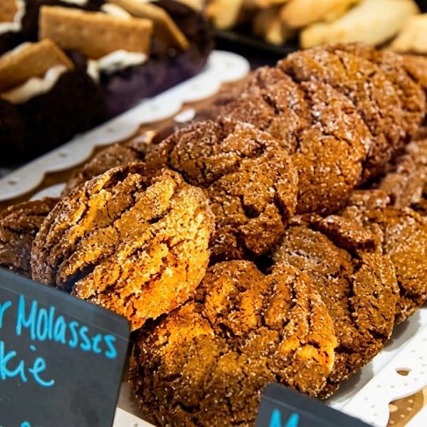 Close-up of ginger molasses cookies on a white tray, with a small sign in front.